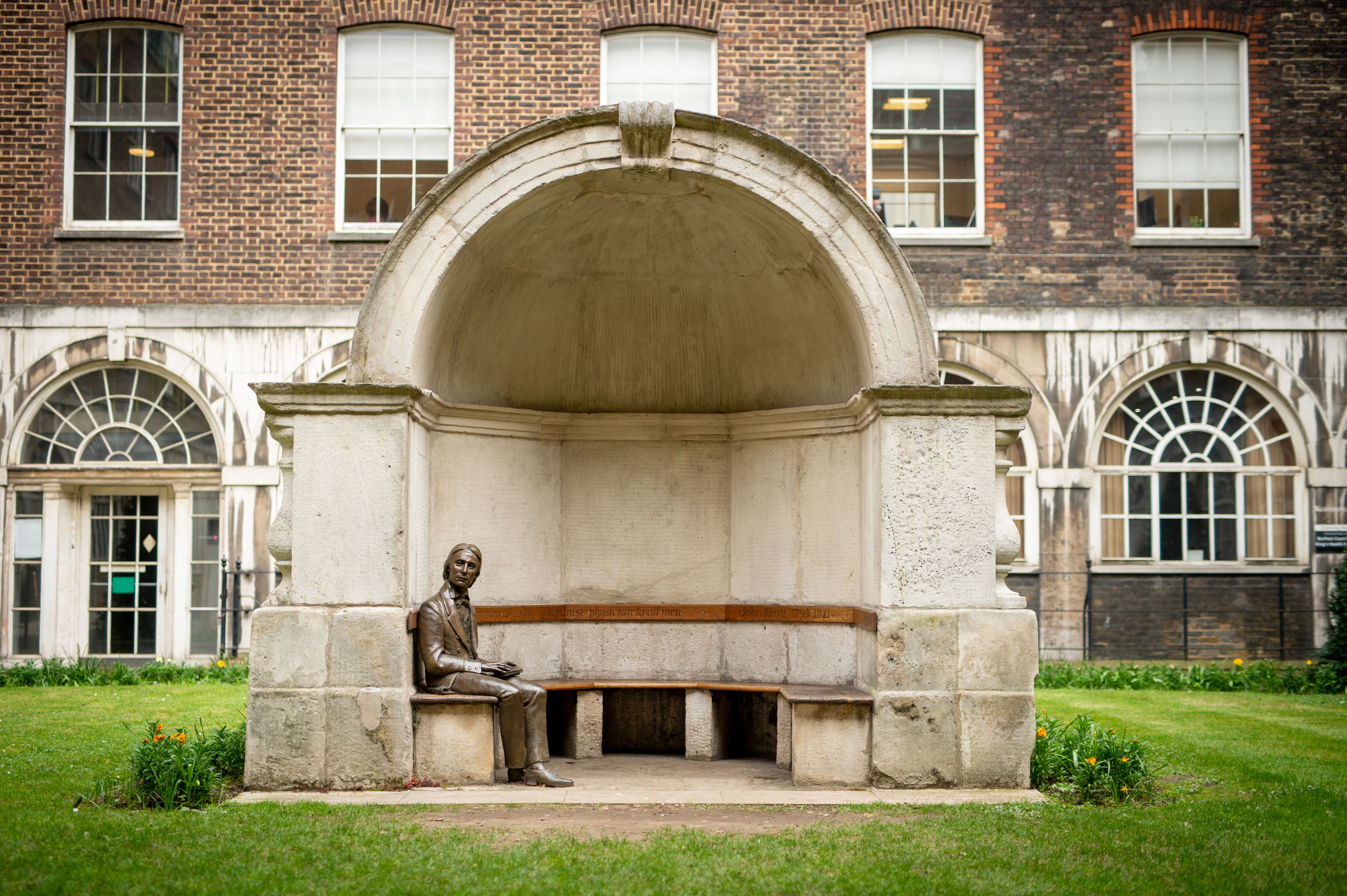 The bronze statue of the poet Keats sitting on a bench in an alcove at Guy's Hospital