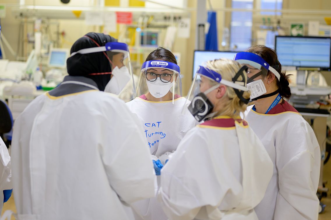 A group of staff in full PPE in a huddle in critical care