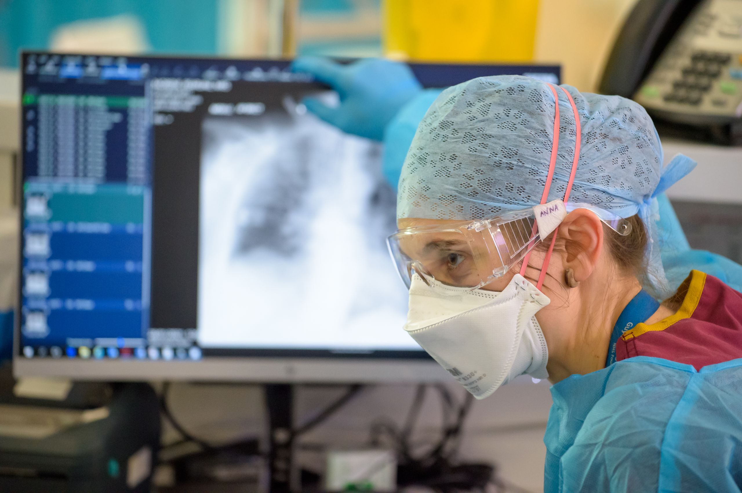 A staff member in PPE with a lung xray in the background