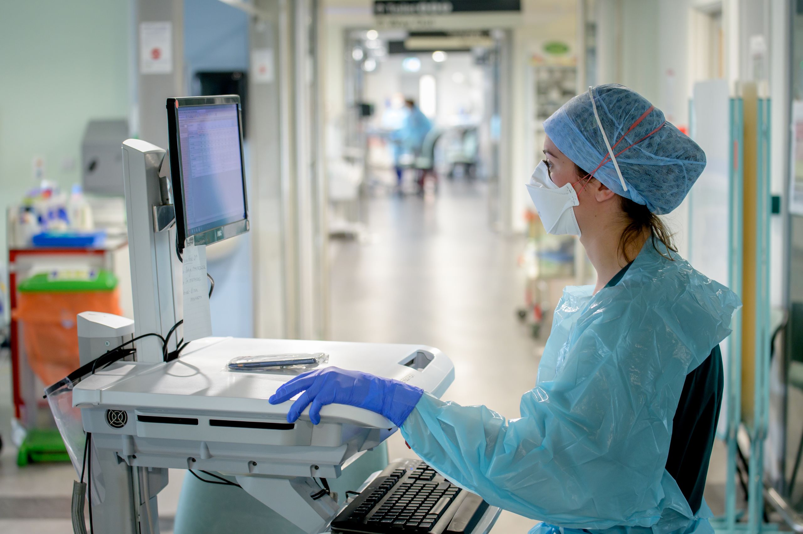 Nurse in PPE working at a computer in intensive care